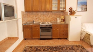 Cocina pequeña con armarios de madera, estufa, pileta y refrigerador.