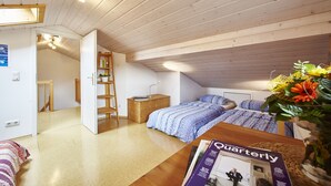 Un dormitorio con cama de altillo, una mesita de noche de madera, una estantería y una revista sobre la mesa.