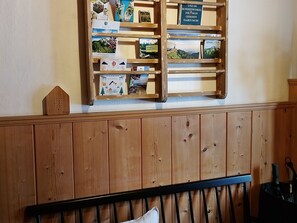 A wooden shelf with books and a small wooden house model.