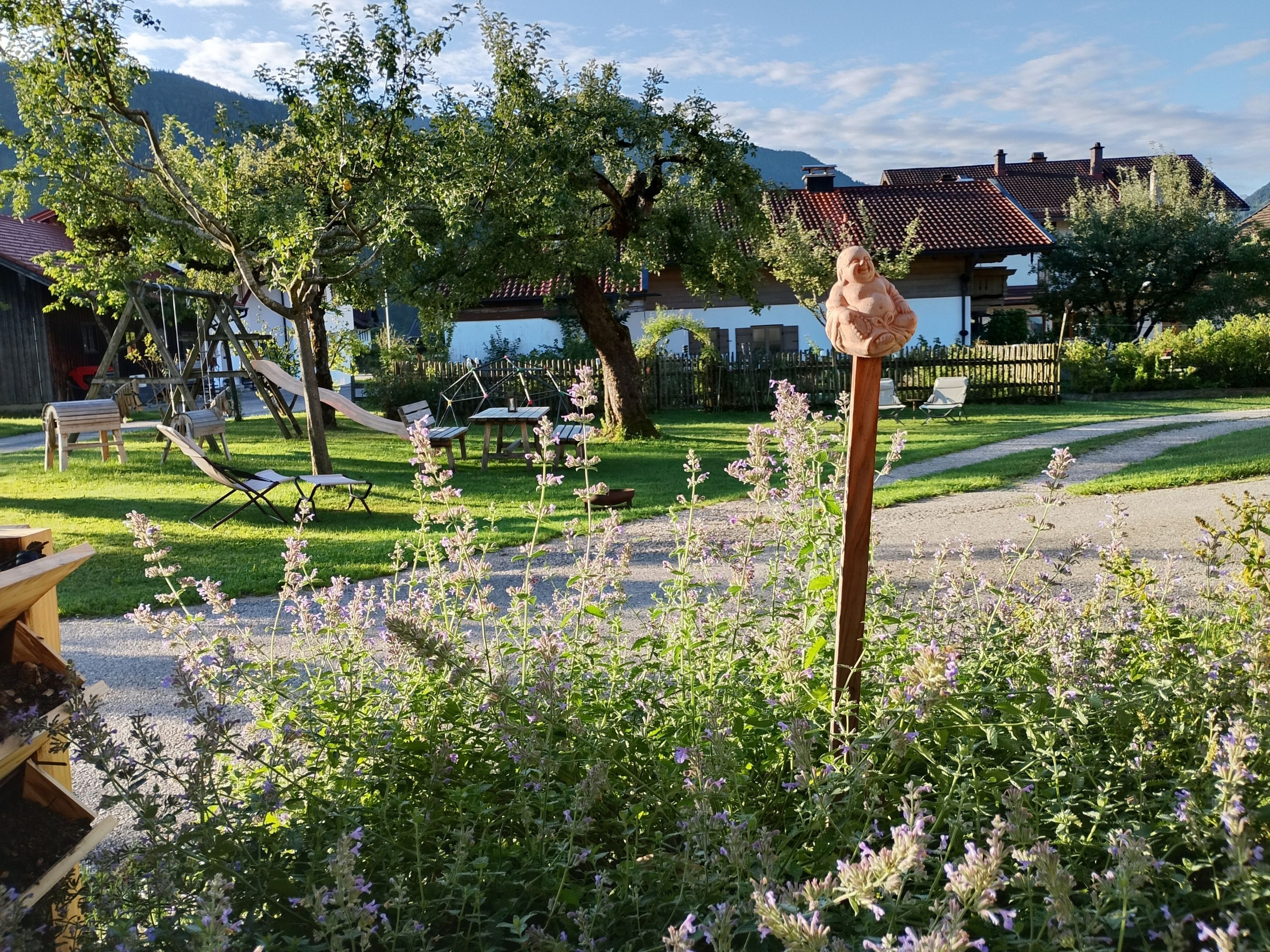 Ein Garten mit einer Holzskulptur, Gartenmöbeln und einem Weg.
