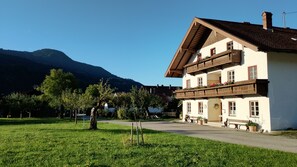 A traditional chalet with a sloped roof, wooden balconies, and a mountain backdrop.