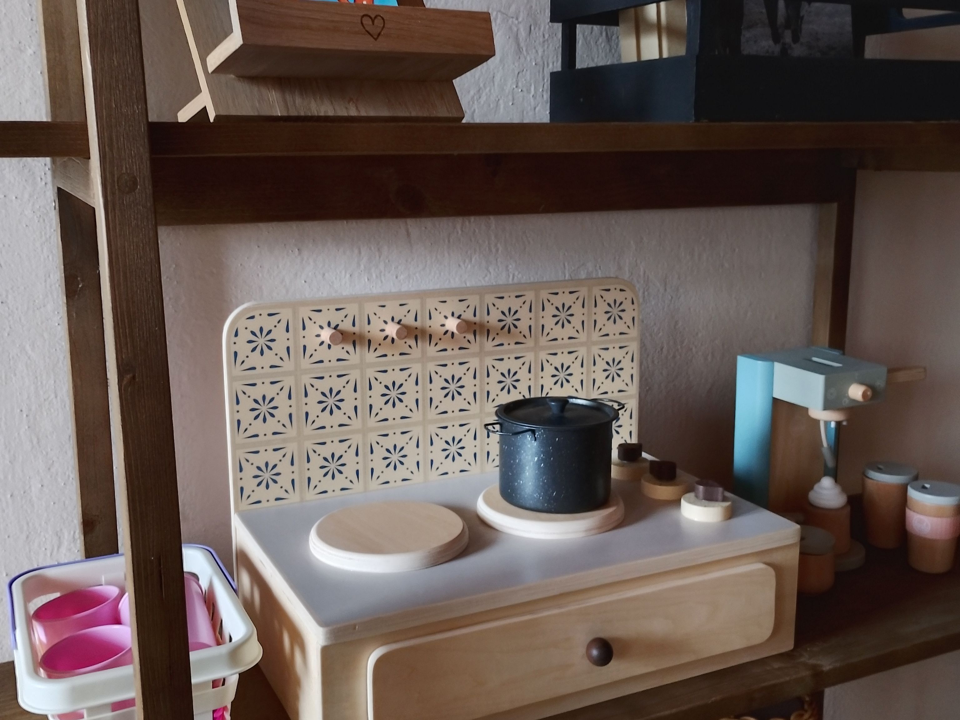 A miniature kitchen setup with a stove, pots, and a sink.