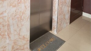 A modern elevator with a control panel, marble-tiled walls, and a door with a doormat. - K&J Apartment (Pattaya)