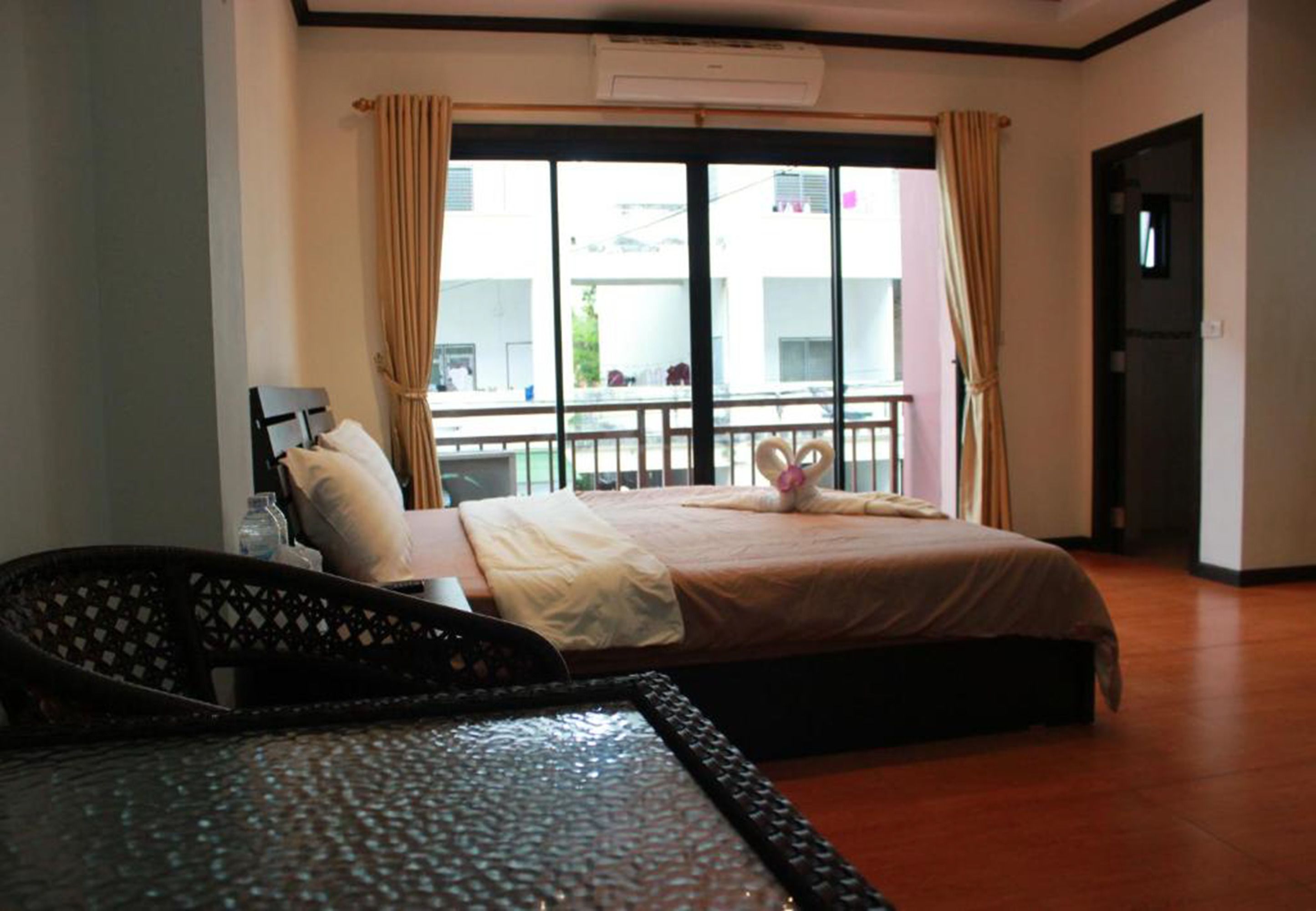 Una habitación de hotel con cama, una silla, una mesa y un balcón con cortinas.