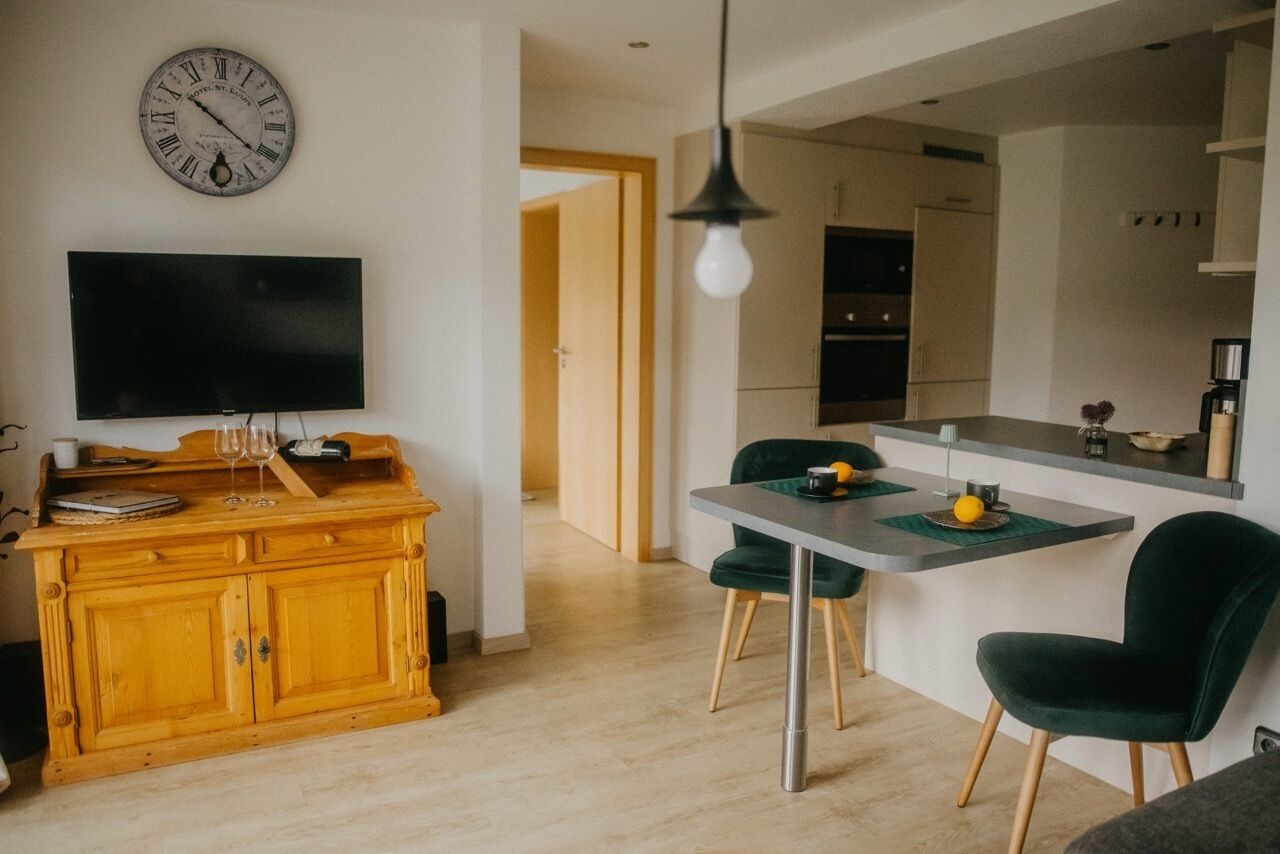 Una cucina moderna con zona pranzo, un armadietto in legno, una TV a schermo piatto e un orologio a parete.