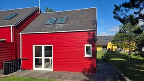 En röd byggnad med ett grått tak, en vit dörr och ett litet fönster.