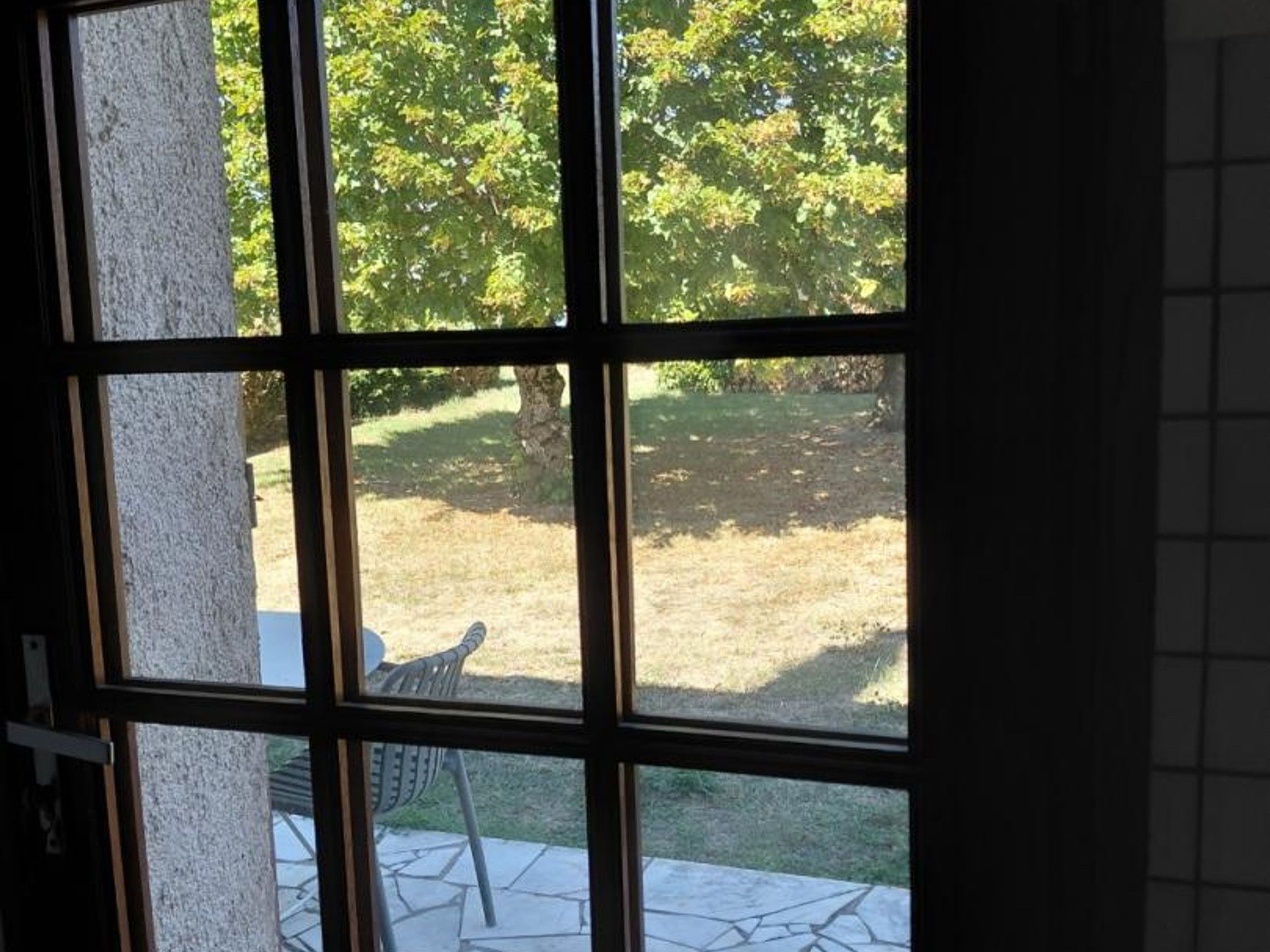A window with a view of a patio area with a chair and a table.