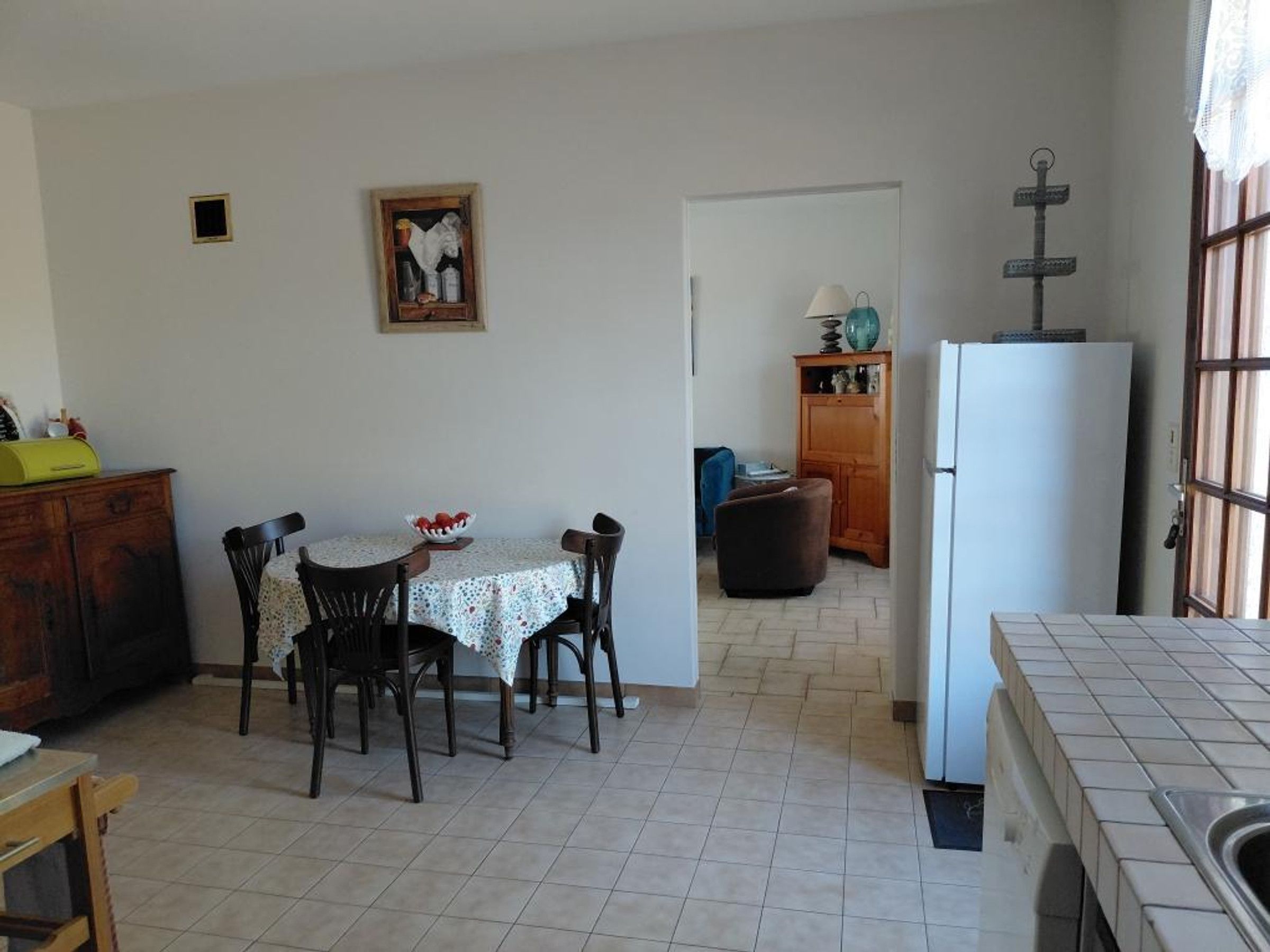 A compact kitchen with a dining table, chairs, a refrigerator, and a cabinet.