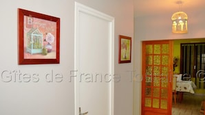 A hallway with a white door, a framed picture of a boutique, and a decorative door with a golden pattern. - Quiet cottage near Azay-le-Rideau Castle (Azay-le-Rideau)