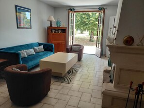 A living room with a blue sofa, a brown armchair, a white coffee table, and a fireplace.