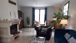 A living room with a fireplace, a blue sofa, a glass coffee table, and a patterned rug. - Quiet cottage near Azay-le-Rideau Castle (Azay-le-Rideau)