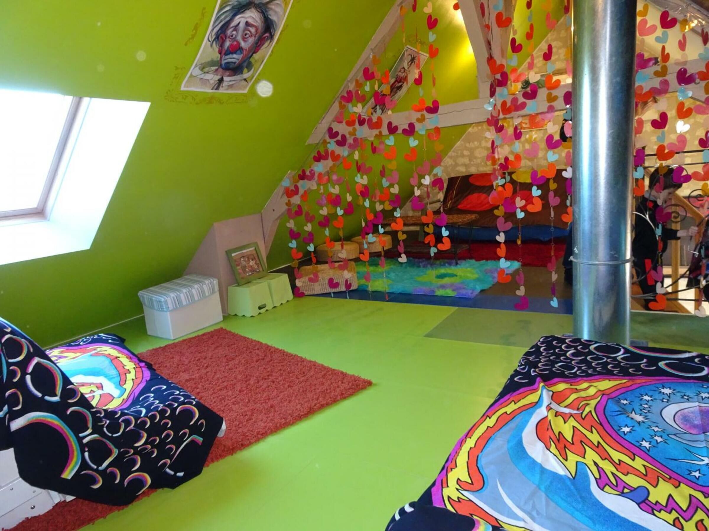 Una habitación colorida con una pared verde, una alfombra roja y una cama con un diseño vibrante.