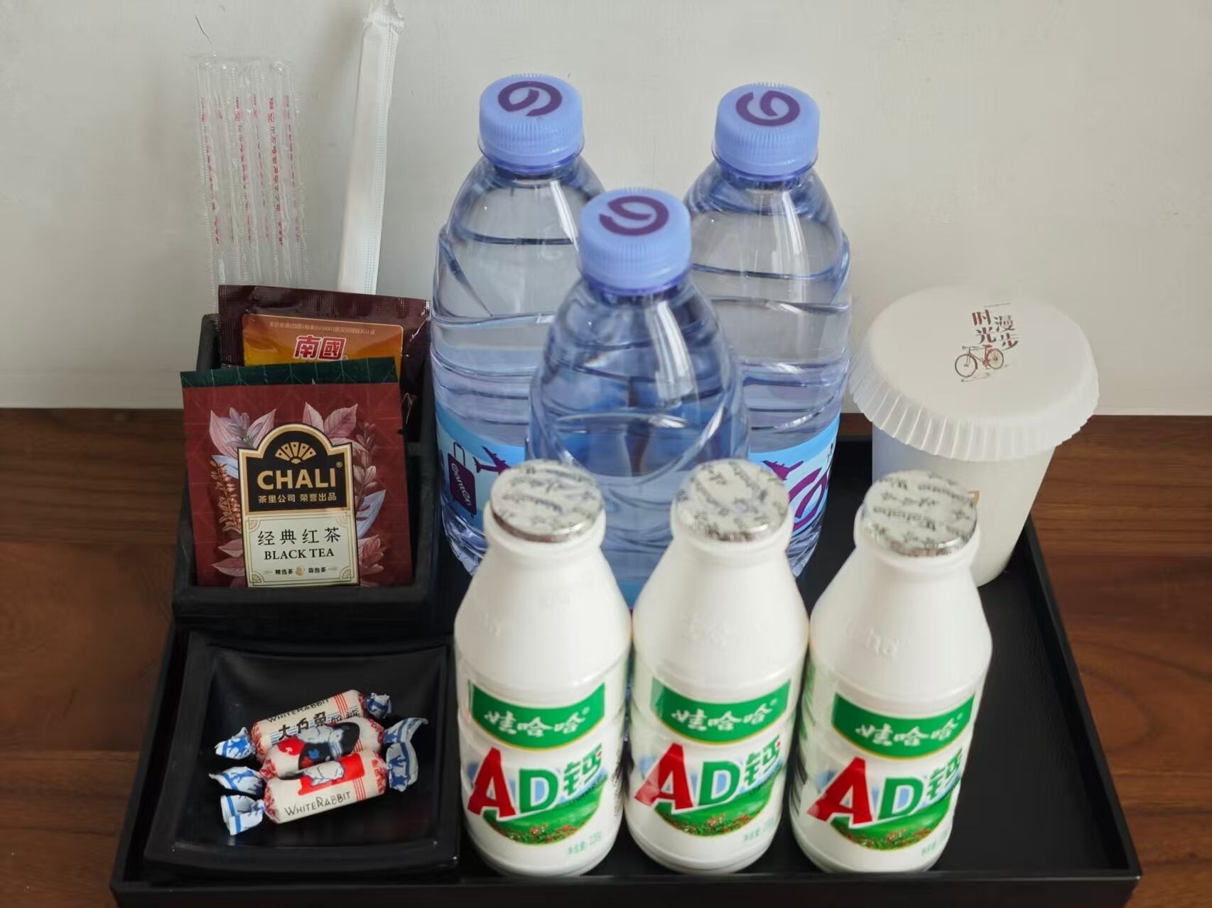 Een dienblad met verschillende spullen, zoals waterflesjes, thee, melk en snacks.