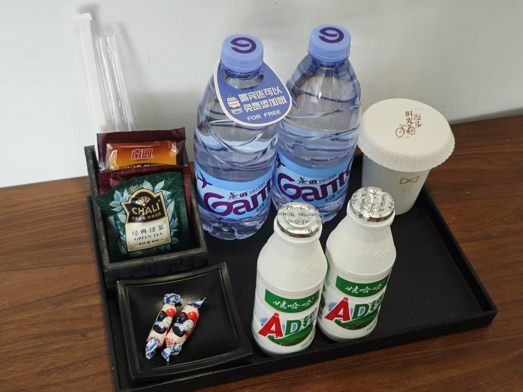 A tray with two bottles of water, a cup, a pack of chai tea, and two bottles of AD drink.