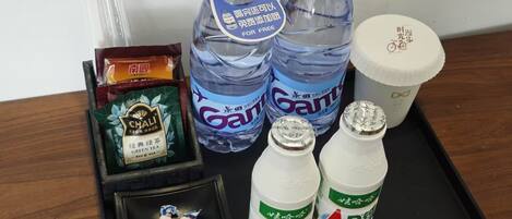 A tray with two bottles of water, a cup, a pack of chai tea, and two bottles of AD drink.