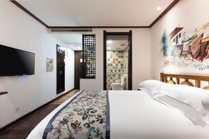 Une chambre d’hôtel avec un lit, une télévision, un mur décoratif et une vue sur la salle de bain.