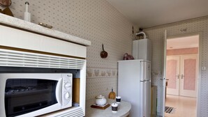 Una cocina compacta con microondas integrado, refrigerador y una pequeña mesa de comedor con sillas.