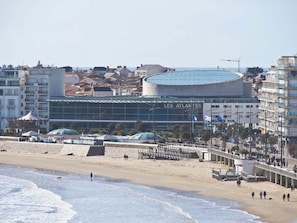 A coastal cityscape with a prominent building labeled 'LES ATLANTES' featuring a modern design with a curved roof and glass facade. - 1-bedroom apartment near the beach with loggia and pet-friendly (Les Sables-d'Olonne)