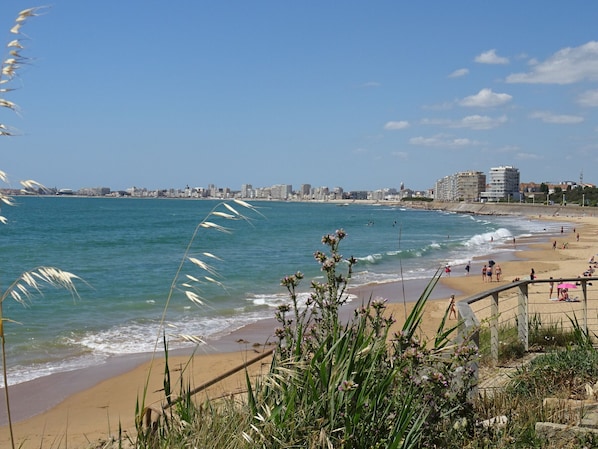 A coastal cityscape with a beach, waves, and a clear sky.