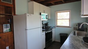 Eine kleine Küche mit Kühlschrank, Herd, Mikrowelle und Spüle.