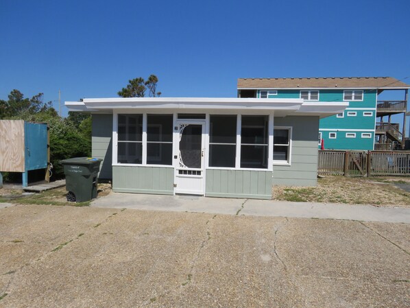 A small, single-story building with a white door and windows, a small porch, and a green exterior. - Summer Special/RIGHT ACROSS from OCEAN/Fenced yard/pet friendly  (Nags Head)
