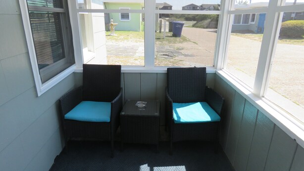Ein Eckzimmer mit zwei Korbstühlen, einem kleinen Tisch und Blick ins Freie.