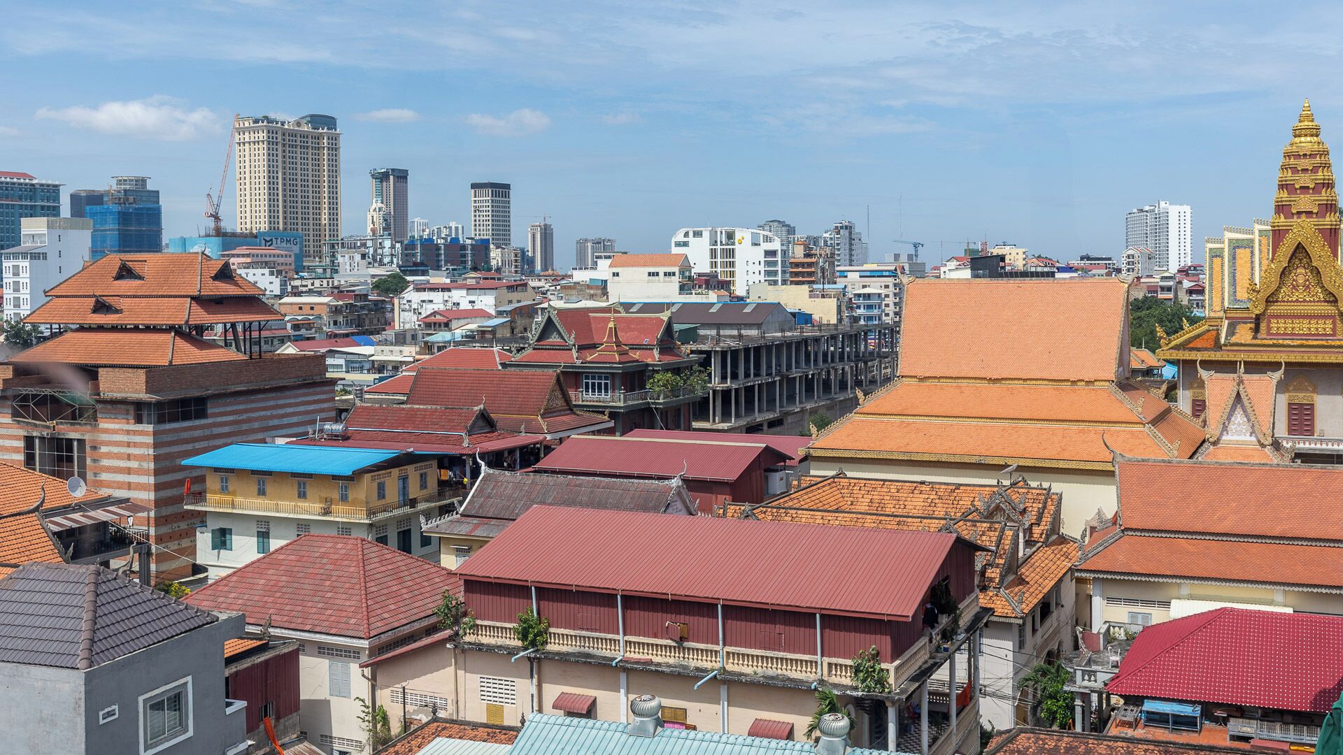 A cityscape with a mix of traditional and modern architecture, including a prominent golden temple.