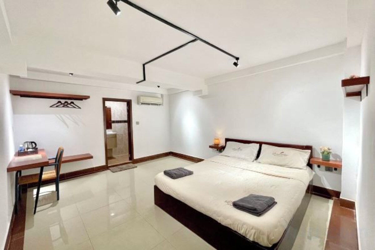 A hotel room with a bed, a desk, and a chair.