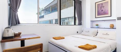 Un dormitorio con cama, mesa, silla y ventana.