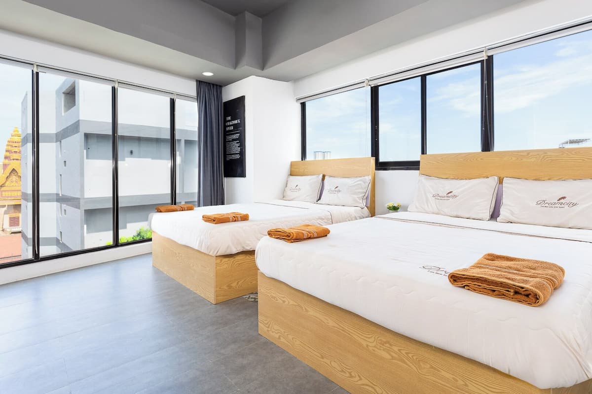 A hotel room with two beds, large windows, and a view of a building with a golden spire.