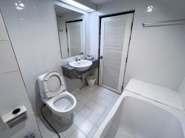 A bathroom with a toilet, sink, mirror, and bathtub.