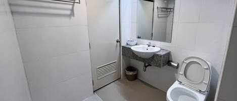 Une salle de bain moderne avec un lavabo blanc, des toilettes et un miroir au-dessus du lavabo.