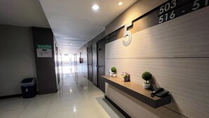 A modern hotel hallway with a reception desk, a phone, and a trash bin. - Srivichai Hotel (Nakhon Ratchasima)