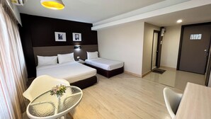 A hotel room with a bed, bedside tables, a small table with a plant, a chair, and a door. - Srivichai Hotel (Nakhon Ratchasima)