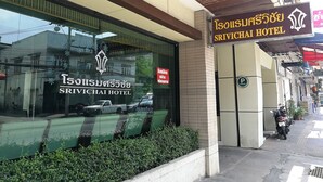 The exterior of the Isousisuraphai Hotel with a large glass window reflecting vehicles and a signboard above the entrance. - Srivichai Hotel (Nakhon Ratchasima)