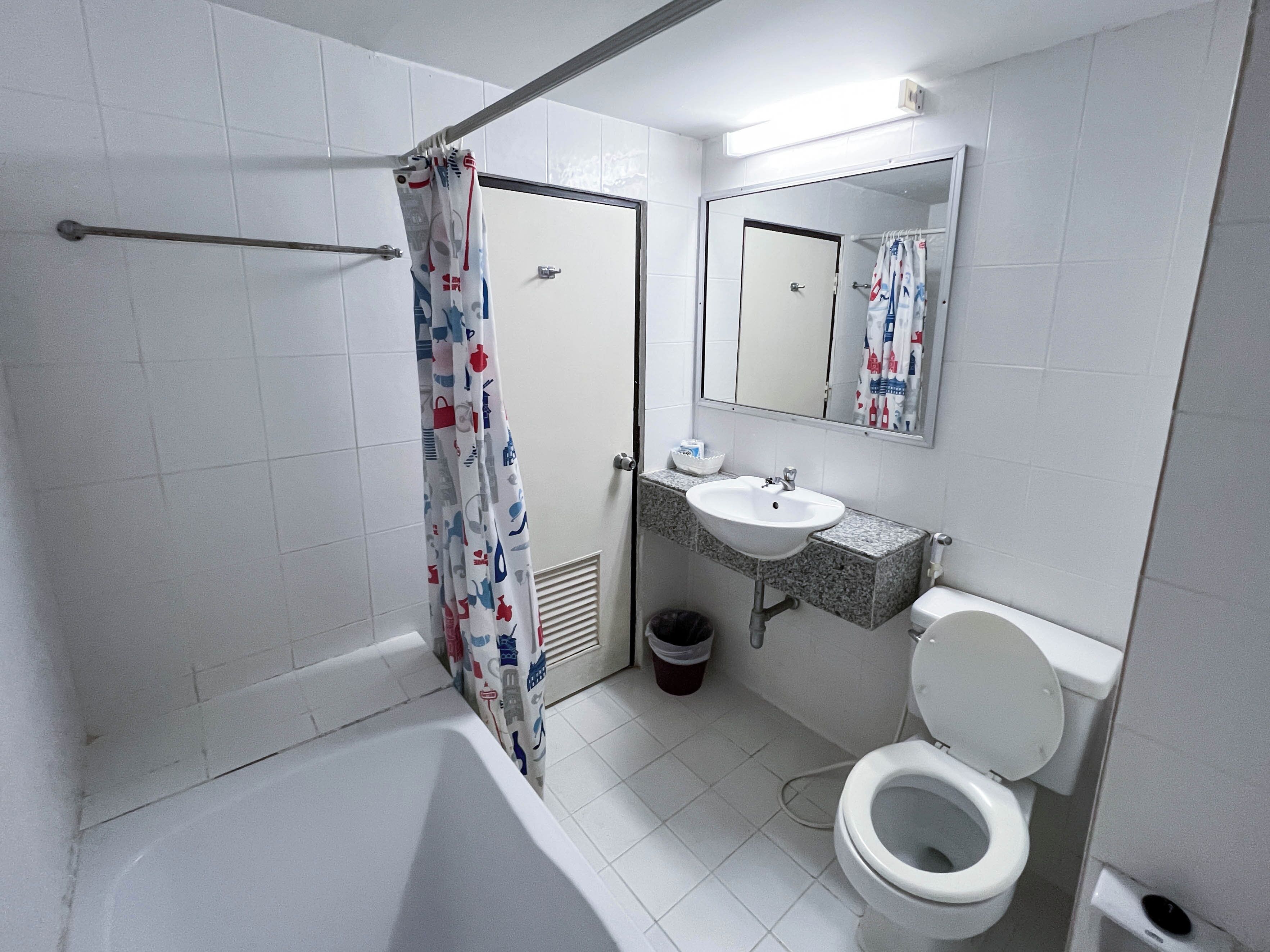 A bathroom with a bathtub, toilet, sink, and a shower curtain with a pattern.