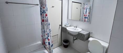 A bathroom with a bathtub, toilet, sink, and a shower curtain with a pattern.
