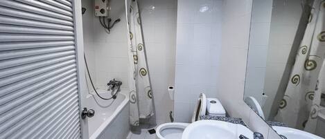 Un baño con bañera, dos lavamanos, inodoro y ducha.