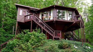 Une cabane en bois avec un escalier, entourée d’une végétation luxuriante.