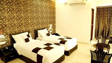 A hotel room with two beds, a small table, and a chair.