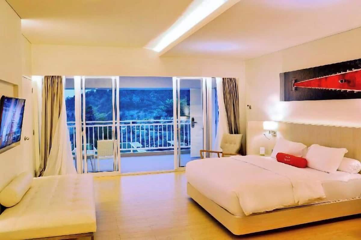 A hotel room with a bed, a sofa, a TV, and a balcony with a view.
