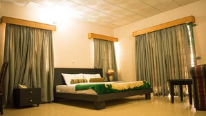 A bedroom with a bed, nightstands, a chair, and curtains. - The Stonehouse Hotel (Lekki)