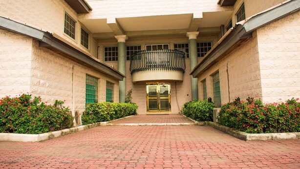 A building with a central entrance, flanked by two wings with windows and columns. - The Stonehouse Hotel (Lekki)