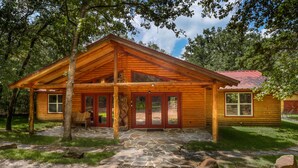 A wooden cabin with a stone-paved entrance, a covered porch, and a red roof. - Luxury Log Cabin in the Premier Resort-Holly Lake Ranch (Holly Lake Ranch)