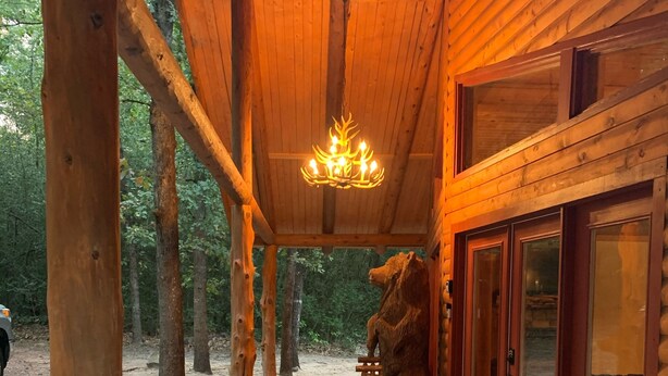 A wooden cabin with a stone-paved entrance, a chandelier, and a bear statue. - Luxury Log Cabin in the Premier Resort-Holly Lake Ranch (Holly Lake Ranch)