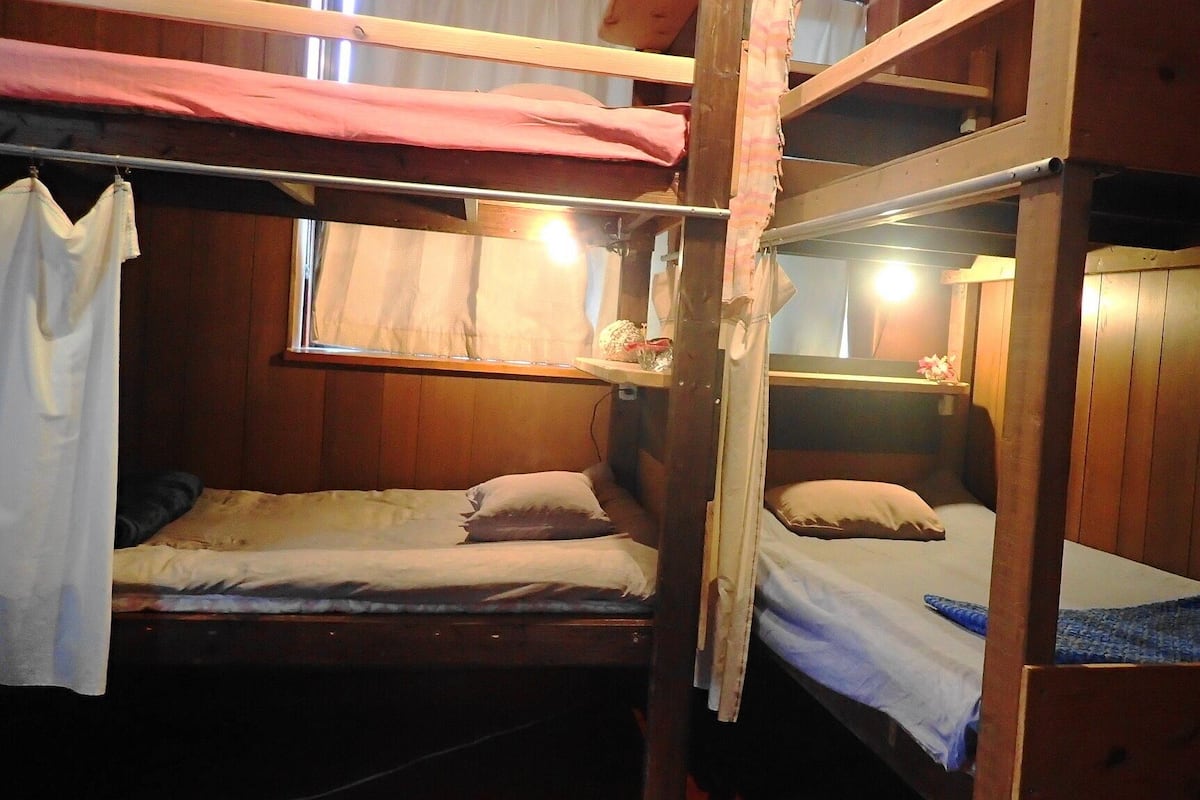 Dormitorio con literas, paredes de madera y ventana.