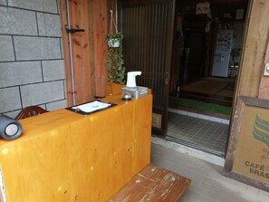 Un comptoir d’accueil en bois, avec un téléphone, un bloc-notes et une petite plante.