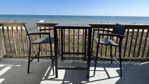 Una terraza de madera con mesa y sillas con vista a la playa.