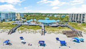 Un hôtel situé en bord de mer, doté d’une promenade, de parasols et de chaises de plage.