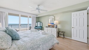 Une chambre à coucher avec un lit, une commode, un miroir et une vue sur l’océan.